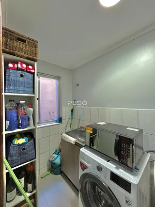 Foto de um ambiente interno mostrando uma área de serviço com máquina de lavar e prateleiras.