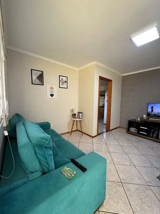 Sala de estar com um sofá azul-turquesa e paredes claras.