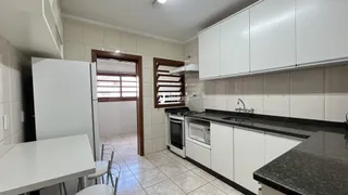 Cozinha com armários brancos e piso de cerâmica em imóvel no Brasil.