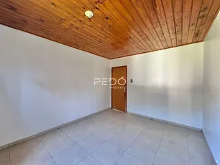 Ambiente interno de uma sala com piso de cerâmica e teto de madeira.