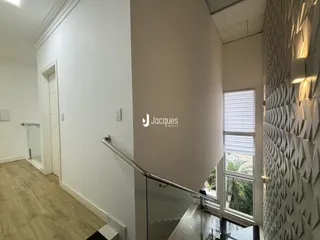 Corredor interno de um apartamento moderno com piso de madeira clara.