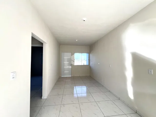 Corredor interno de uma residência com piso de cerâmica clara.