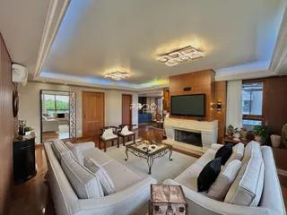 Sala de estar com sofás brancos e lareira em ambiente residencial.