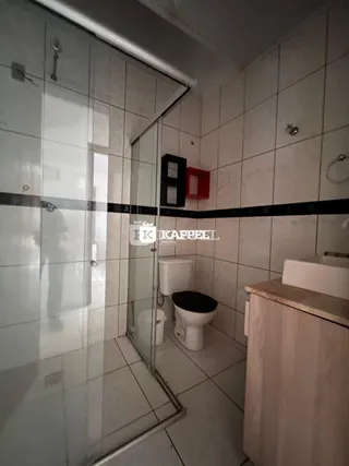 Foto de um banheiro com revestimento de azulejos brancos e box de vidro.