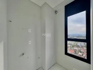 Vista interna de um corredor com paredes brancas e uma grande janela.