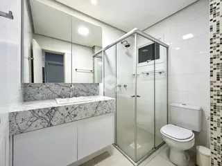 Banheiro com box de vidro e bancada de mármore.