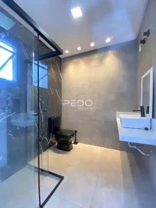 Interior de um banheiro moderno com revestimento em mármore e box de vidro.
