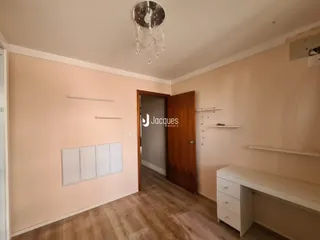 Interior de uma sala com piso de madeira e paredes claras.