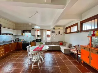 Ambiente interno de sala de estar com cozinha integrada e piso de cerâmica marrom.