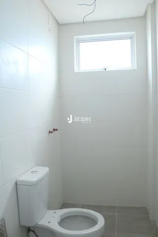 Foto interna de um banheiro branco com vaso sanitário.