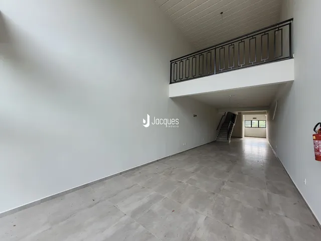 Hall de entrada com piso de concreto e varanda.