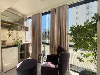 Sala de estar com grandes janelas e cortinas claras.