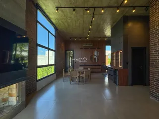 Interior de uma sala de estar com grandes janelas e teto alto em um imóvel em Lajeado.