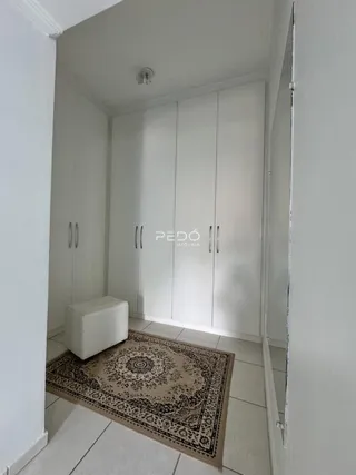 Hall de entrada com armários brancos e tapete no piso.