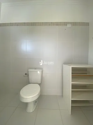 Foto de um banheiro com piso e paredes revestidos de azulejos brancos.