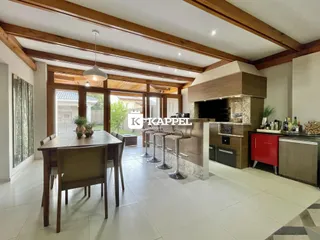 Uma sala de jantar ampla com cozinha integrada e ilha central em um ambiente com vigas de madeira.