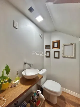 Um banheiro com vaso sanitário e pia de cerâmica sobre uma bancada de madeira.