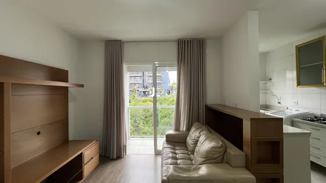 Sala de estar com piso de madeira e porta de vidro.