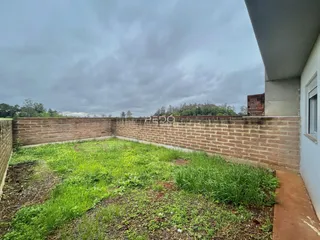 Parede de tijolos e grama com vegetação em uma propriedade.