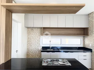 Vista da cozinha moderna com armários brancos e bancadas escuras.