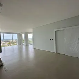 Foto de um ambiente interno amplo com piso claro e grandes janelas.