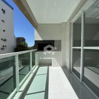 Vista de uma varanda moderna com piso de cerâmica clara e grade de vidro.