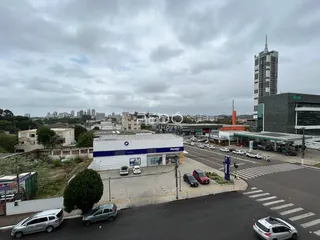 Vista externa de uma propriedade com estacionamento e edifícios ao fundo.