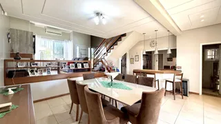 Sala de jantar com mesa de madeira e escadaria visível no interior da residência.