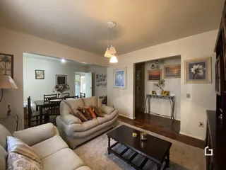 Sala de estar com sofá e piso de madeira em uma residência.