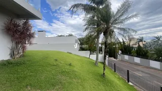 Fachada de uma residência com gramado e palmeiras ao lado de uma estrada.