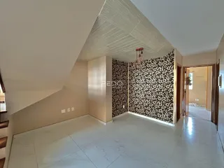 Uma sala com teto inclinado e parede com papel de parede estampado.