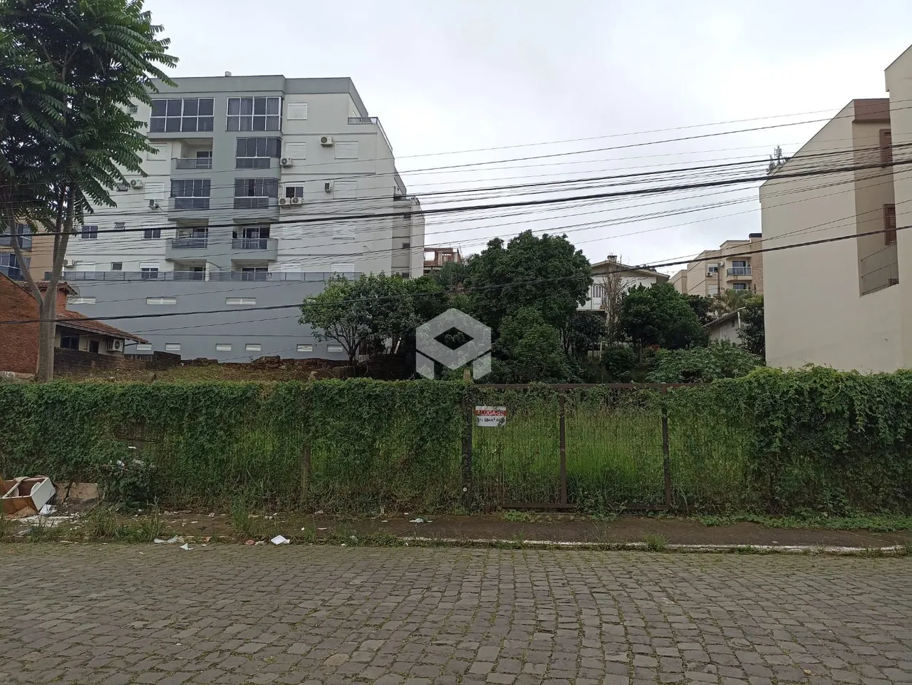 Vista externa de edifícios residenciais em Lajeado, Brasil, com vegetação e cerca.