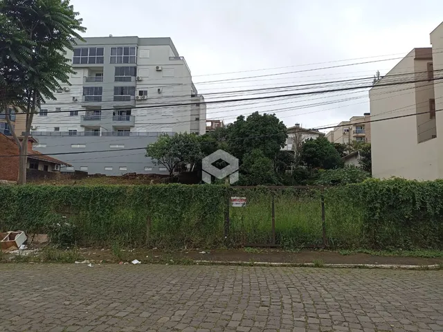 Vista externa de edifícios residenciais em Lajeado, Brasil, com vegetação e cerca.