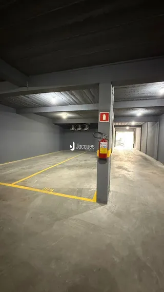 Corredor interno com piso de concreto e marcações amarelas.