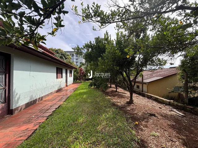 Vista lateral da fachada de uma residência com jardim e calçada de tijolos.