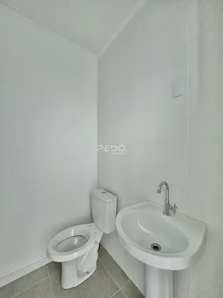 A foto mostra o interior de um banheiro com louças sanitárias brancas.