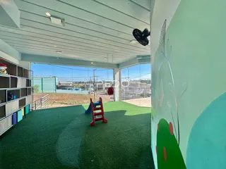 Espaço aberto com piso de grama sintética e acesso ao quintal.