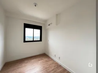 Sala de estar com piso de madeira e janela para a vista da cidade.