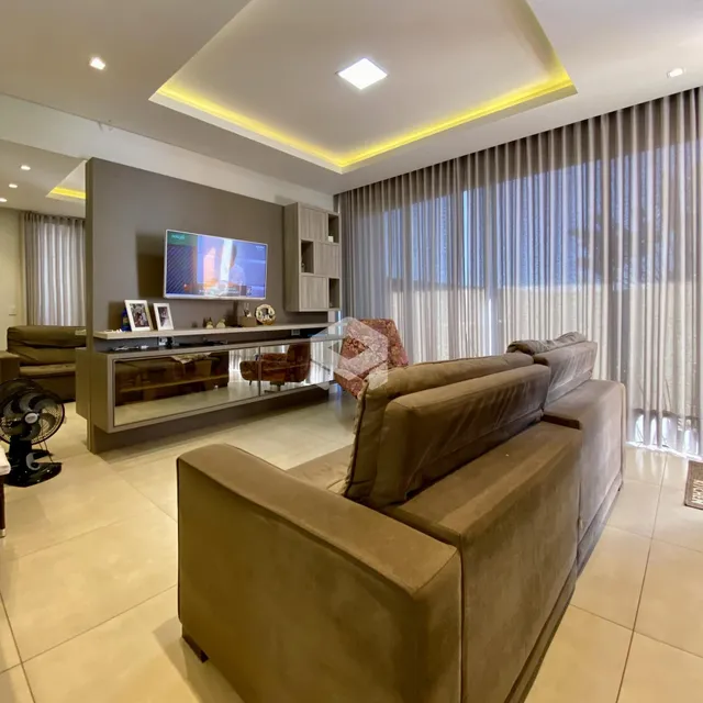 Sala de estar moderna com sofá e televisão em um ambiente bem iluminado.