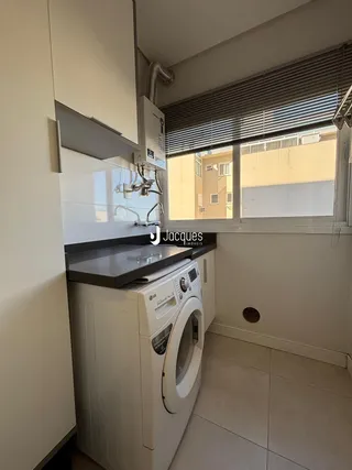 A cozinha exibe armários brancos e uma máquina de lavar roupa.