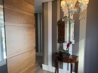 Hall de entrada com painéis de madeira e lustre ornamentado.