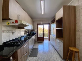 Interior de uma cozinha com armários de madeira e piso de cerâmica.