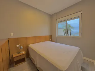 Quarto com cama de casal e janela com vista para a paisagem.