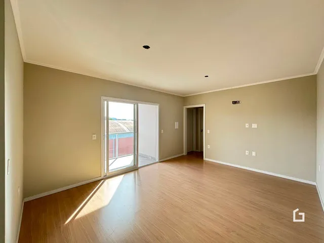 Sala ampla com piso de madeira clara e porta de vidro.
