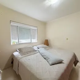 Quarto com cama de casal e paredes claras.