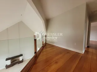 Interior de um ambiente com piso de madeira e paredes brancas.