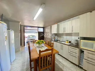 Vista de uma sala de jantar com mesa de madeira e cozinha em um imóvel no Brasil.