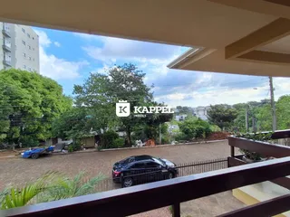 Vista externa de uma área com carros e vegetação.