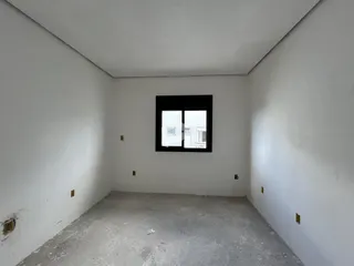 Imagem de um cômodo vazio com paredes brancas e piso de concreto.