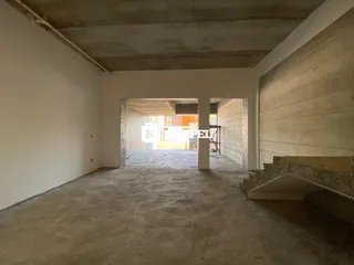 Interior de um espaço com teto de concreto aparente e paredes brancas.